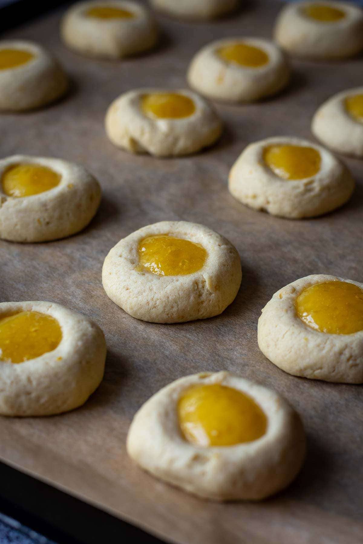 Baked Lemon Thumbprints with lemon curd on a baking sheet.