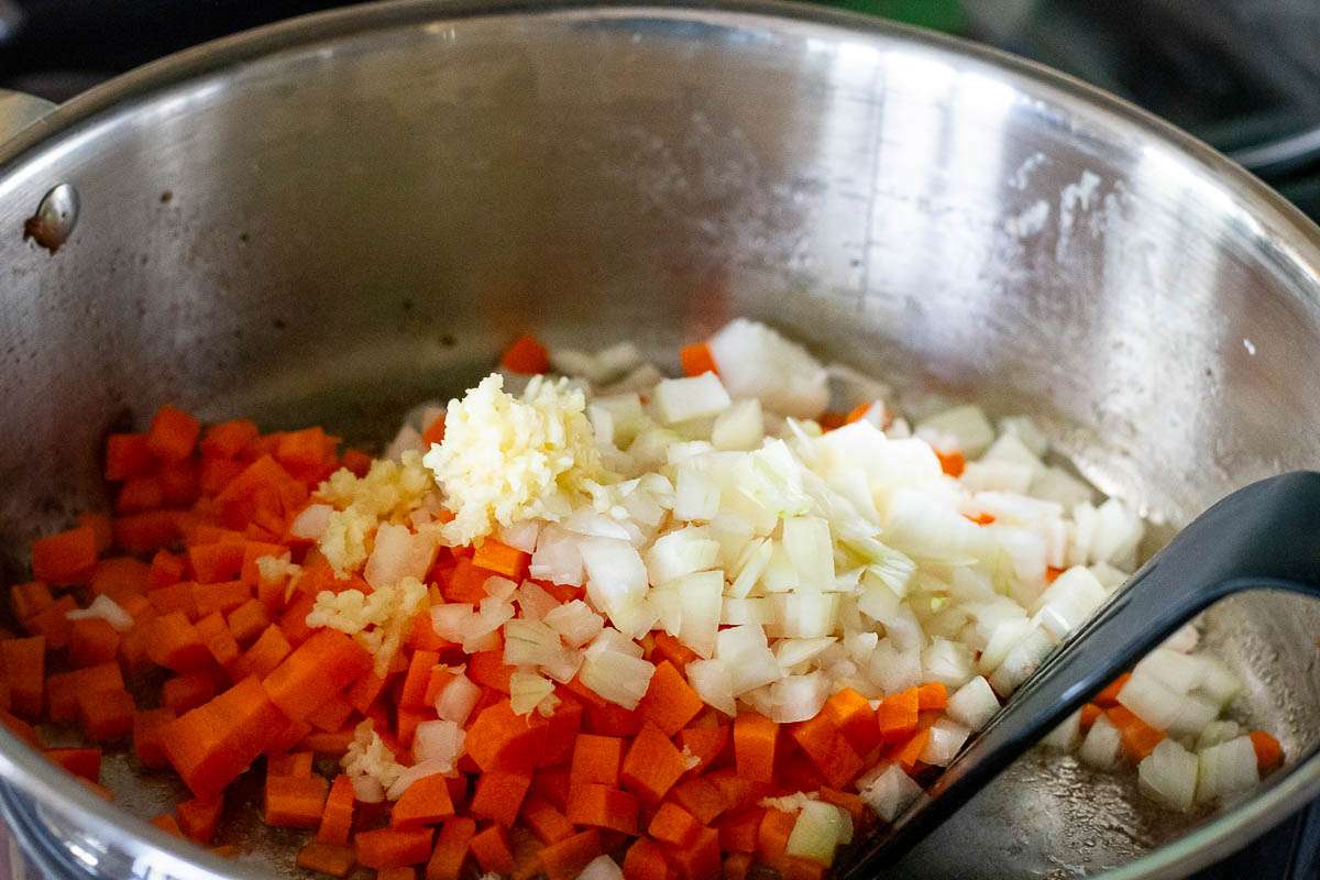Sauteeing carrots and onions in a large pan.
