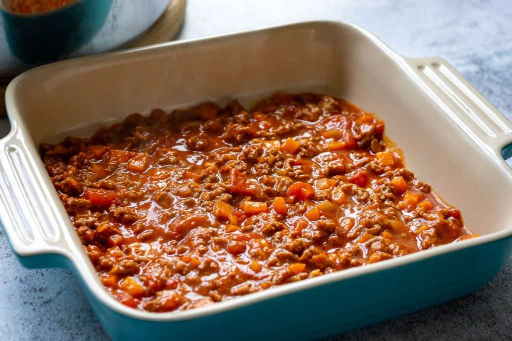 First layer of beef ragu in a ceramic ovenproof dish.
