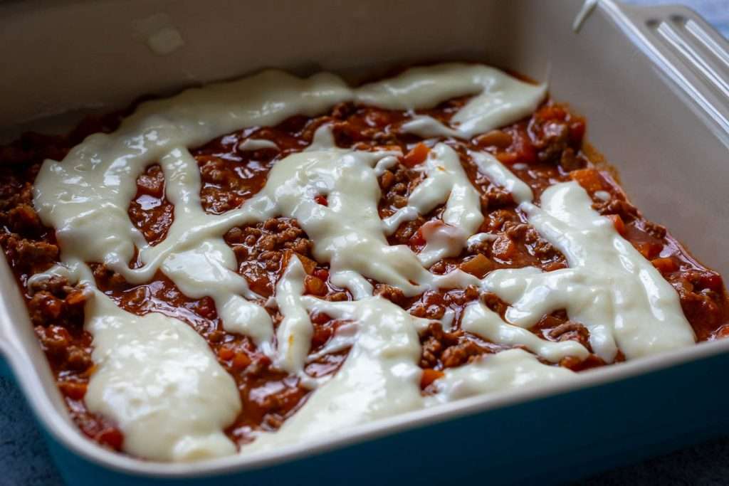 Bechamel sauce poured over beef ragu.