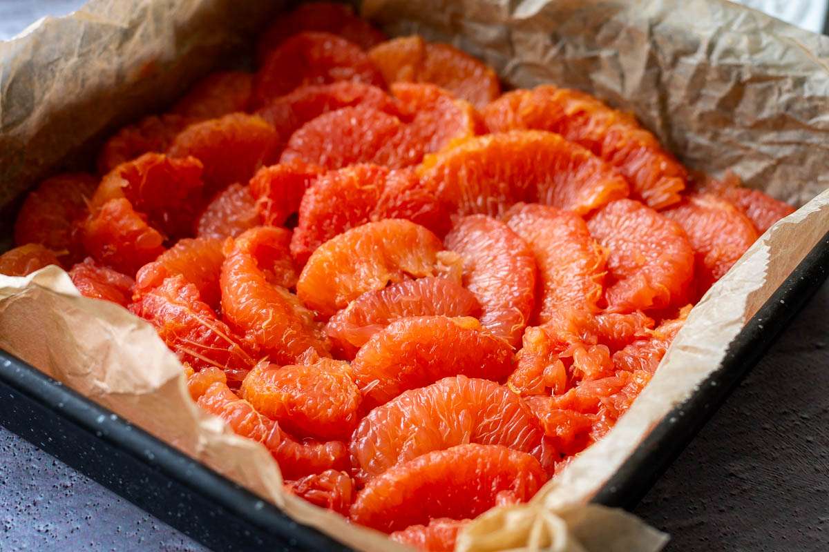 Grapefruit segments arranged on the base of a square baking tin.