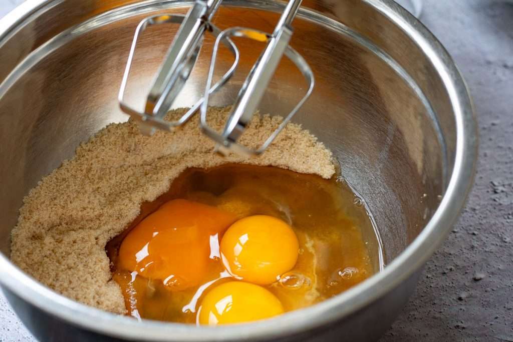 Eggs and sugar in a large metal bowl.