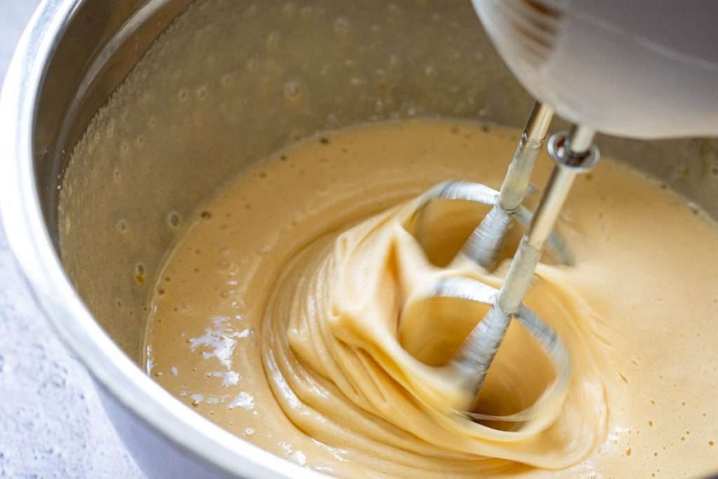 Egg mixture being beating with an electric handheld mixer.