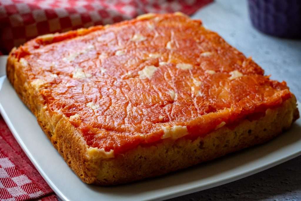 Grapefruit cake with parchment paper unpeeled, esposing the grapefruit segments.