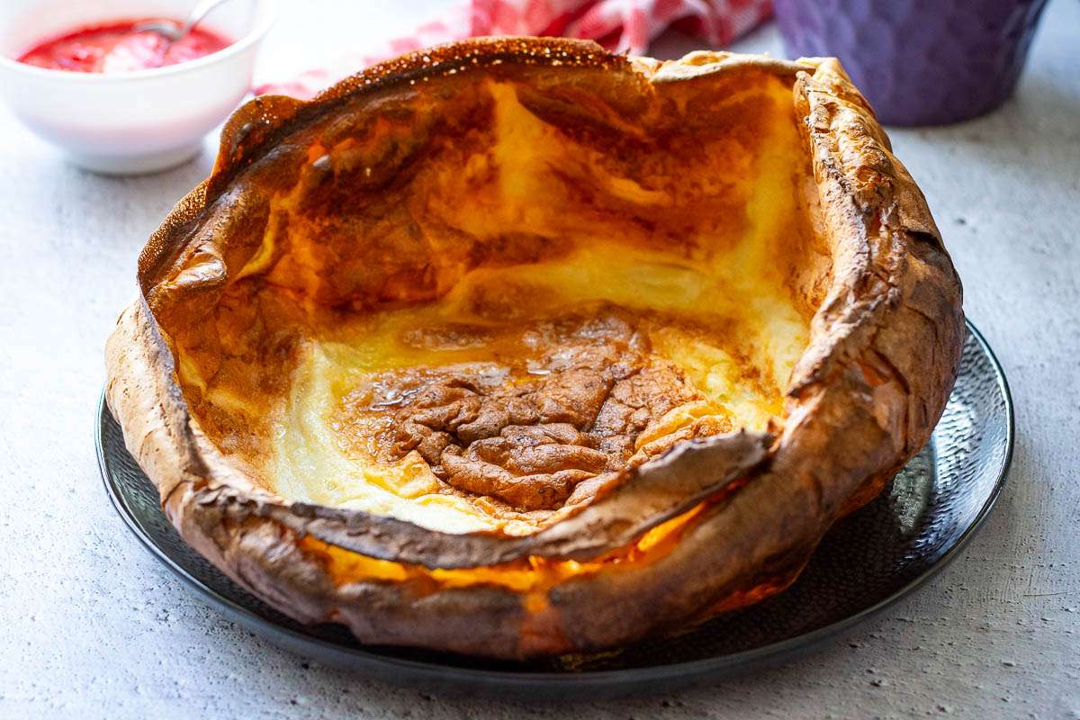 Giant Dutch Baby on a black plate without any toppings.