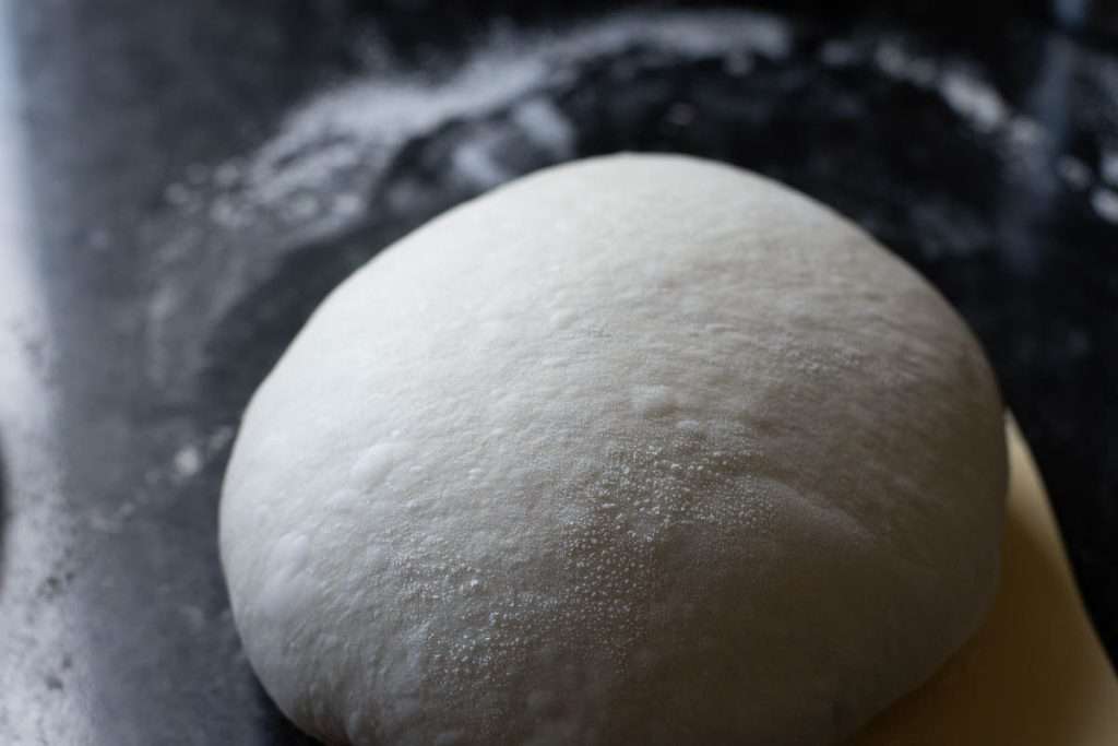 Sourdough shaped into a tight ball on a kitchen surface.