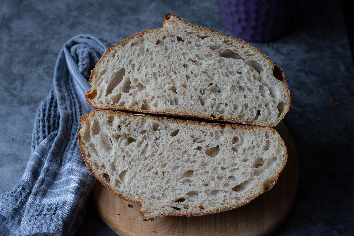 Sourdough loaf cut in half on a wooden chopping board.