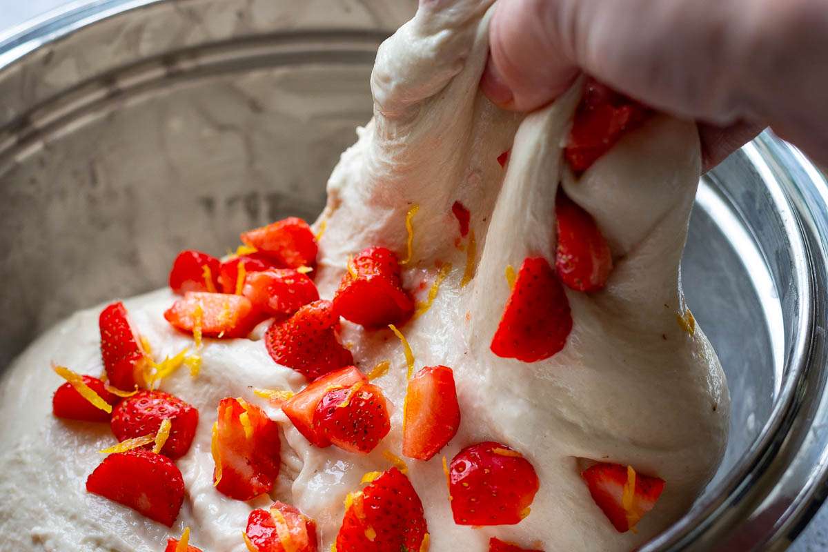 Stretching and folding the dough over the into the centre to incorporate th strawberries into the dough.