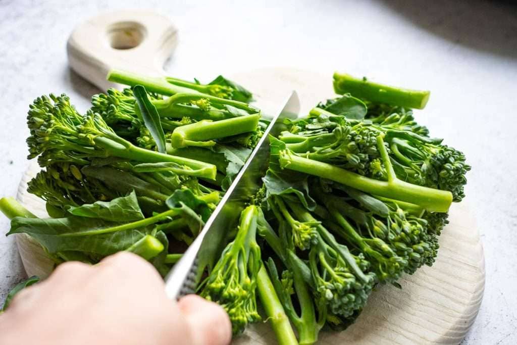 Cutting tenderstem broccoli in half.