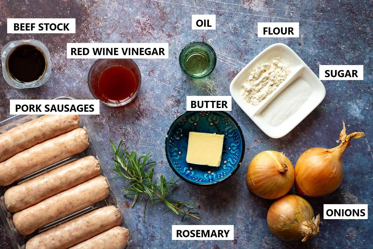 Ingredients for Sausages with onion gravy on a rustic table surface.