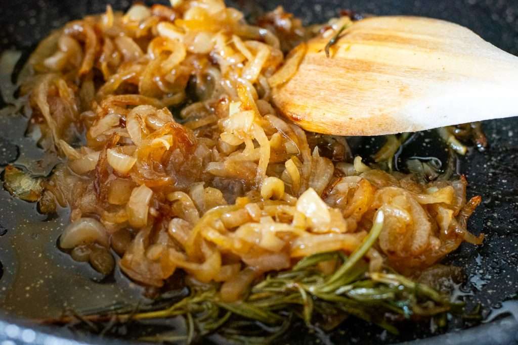 Caramelising onions in a large frying pan.