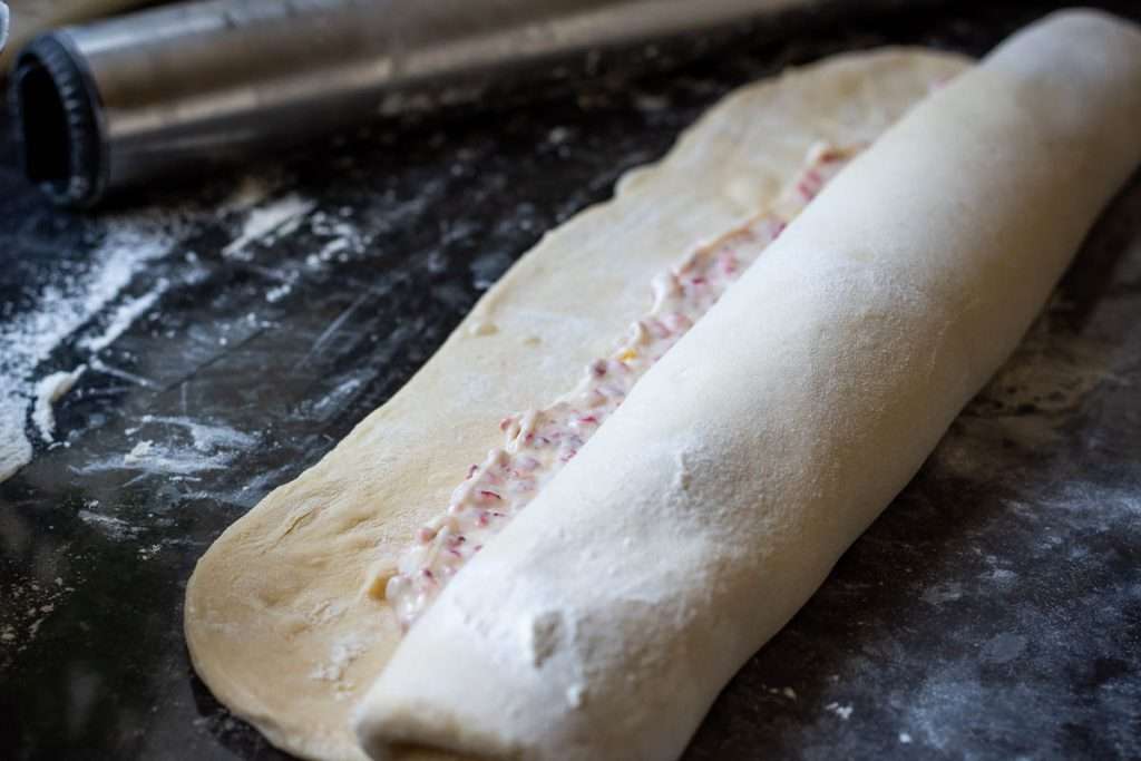 Rolling the babka dough with filling into a tight log.