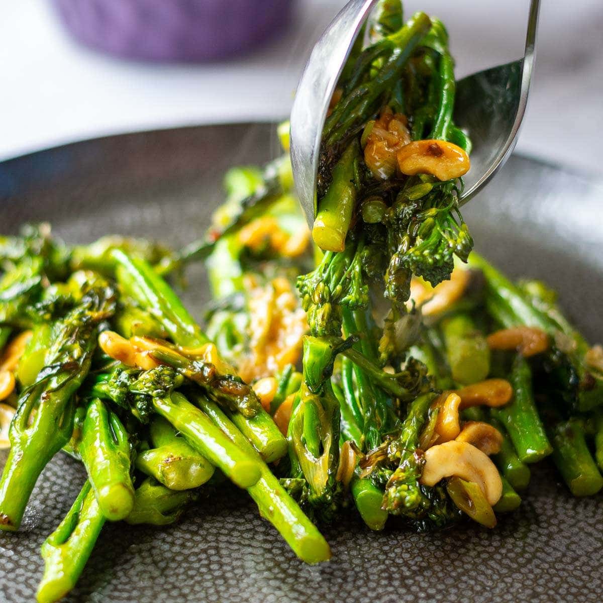Stir Fried Tenderstem Broccoli with Pyster sauce being placed on a large black plate.