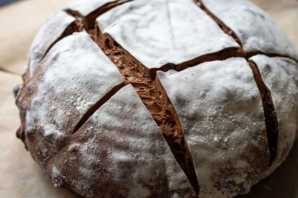 Scored sourdough bread on a sheet of parchment paper.