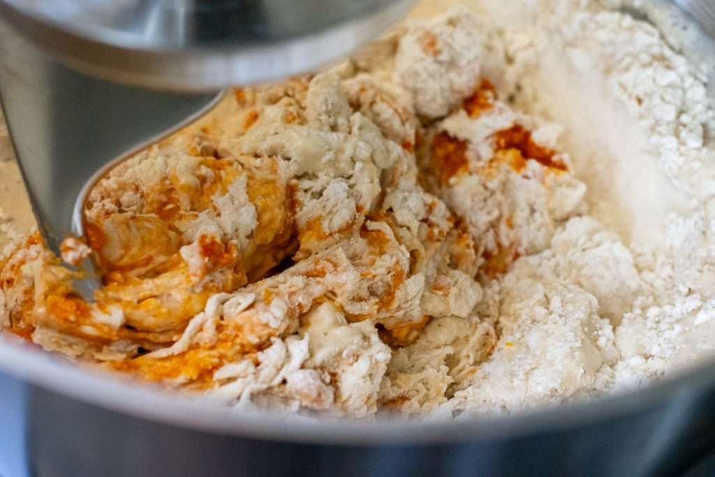 Stand mixer fitted with a dough hook attachment mixing the pumpkin sourdough.