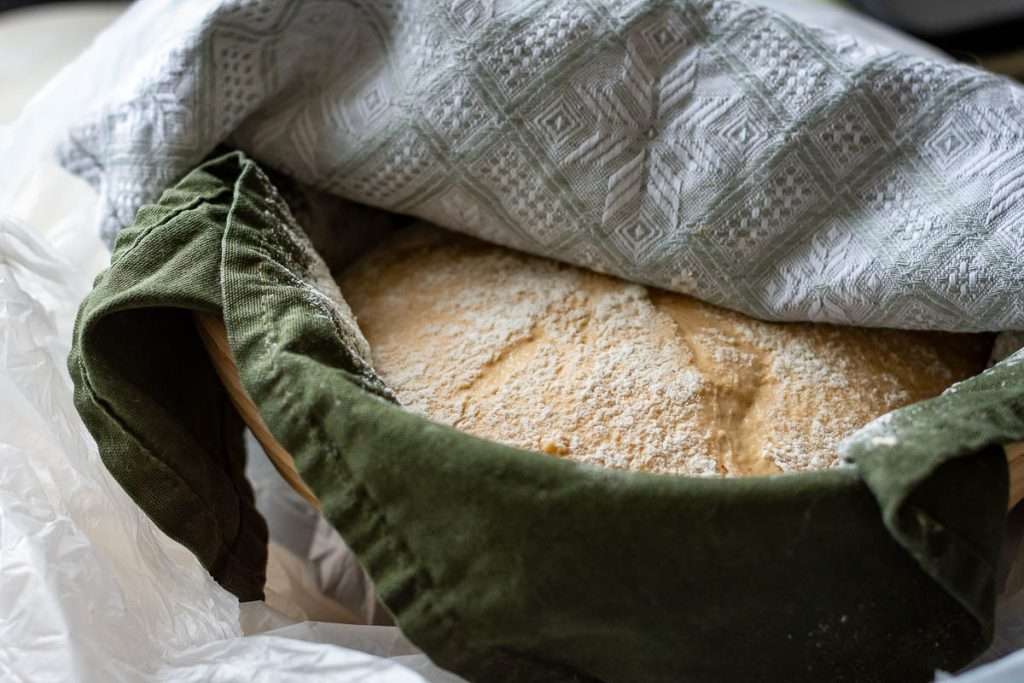 Shaped pumpkin sourdough in a floured basket.