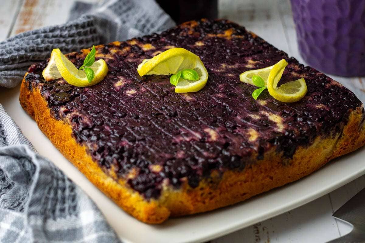 Inverted Blackcurrant upsidedown cake on a square white plate.