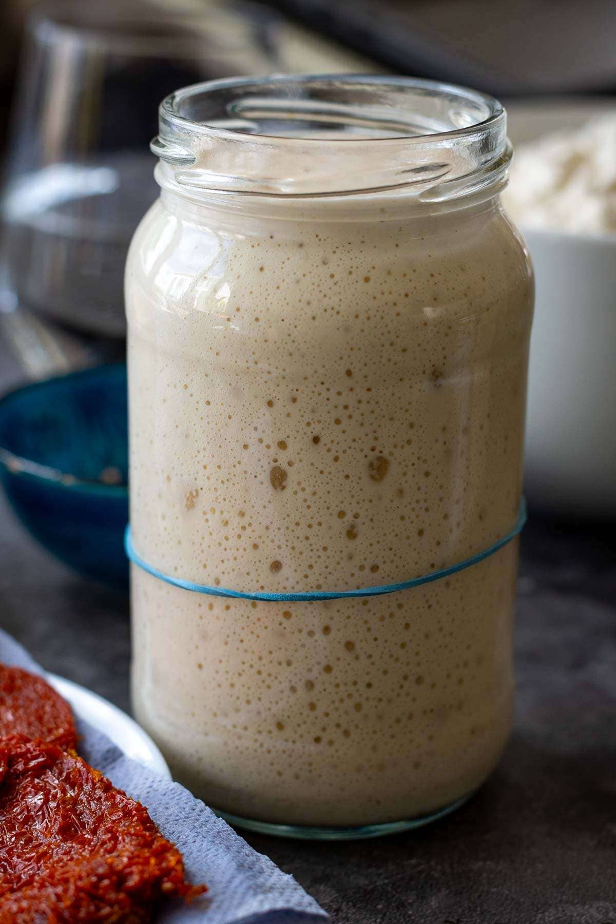 Active and bubbly sourdough starter in a glass jar.