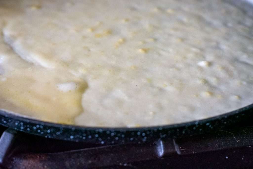Crepe cooking on the first side in a crepe pan.