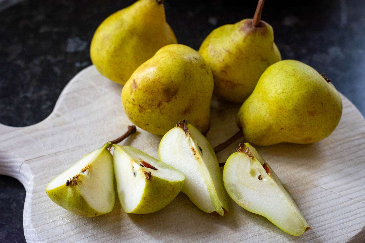 Pears being quartered on a wooden chopping board.