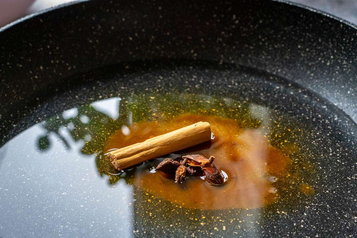 Water, sugar, cinnamon stick and star anise in a pan.