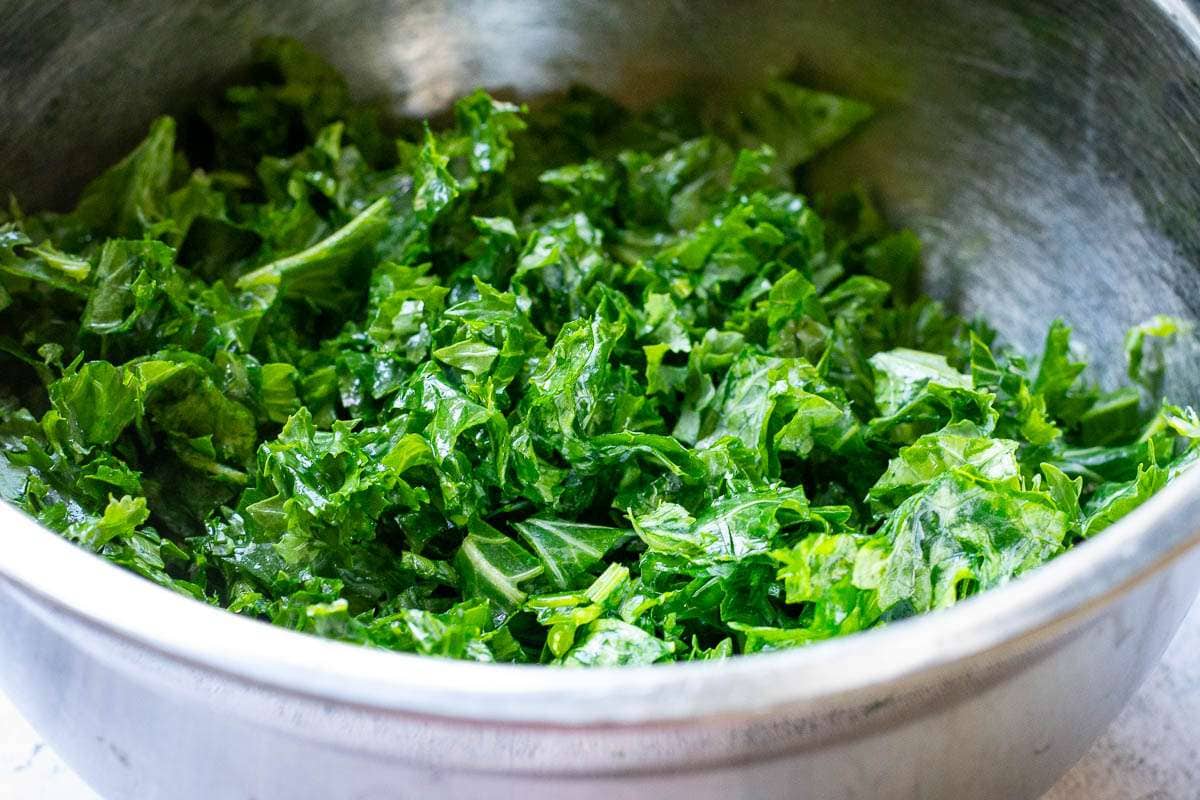 Massaged to soften and shredded kale in a large metal bowl.
