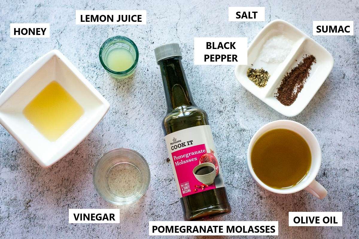 Ingredients for Pomegranate Molasses salad dressing on a grey surface.
