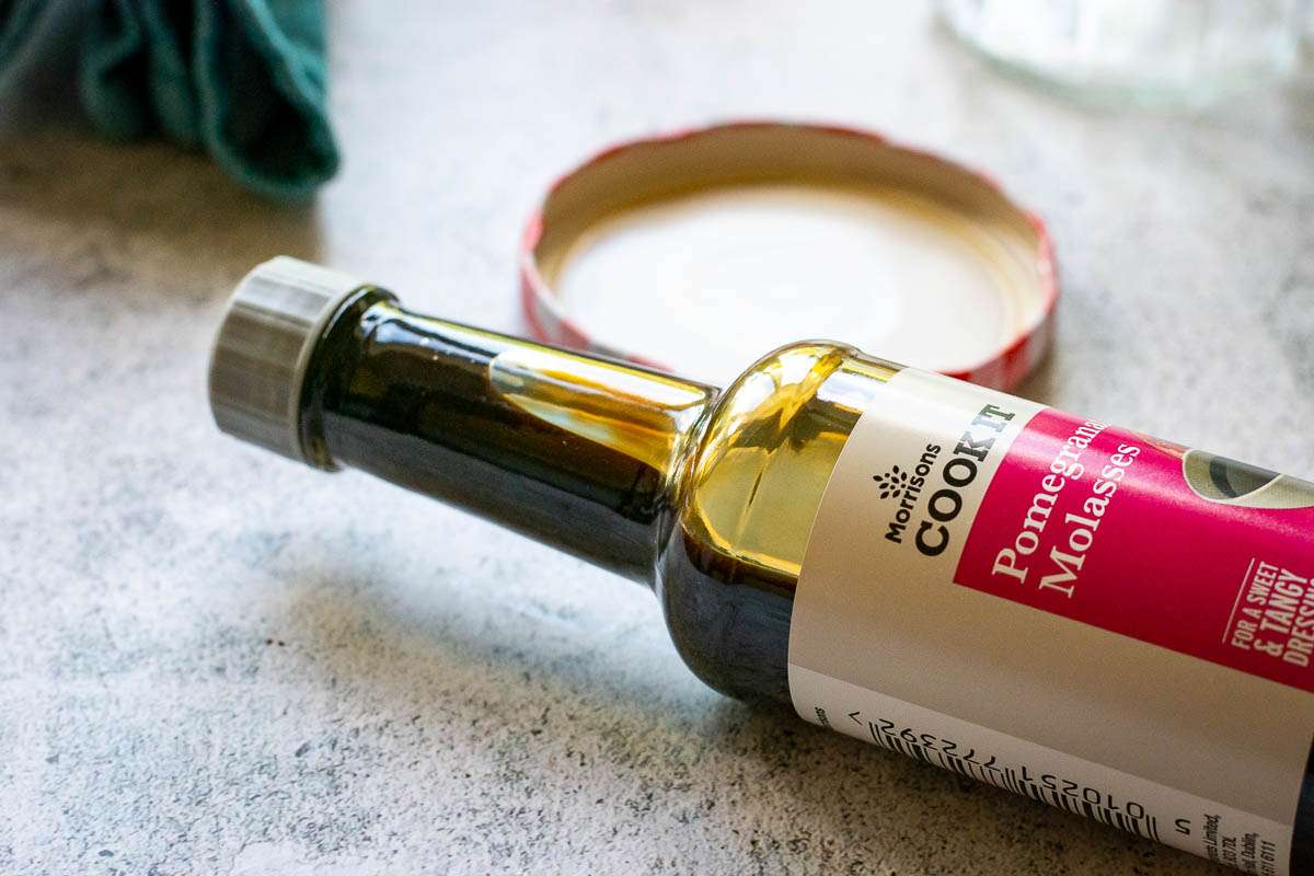 A small bottle of pomegranate molasses vinaigrette on its side.