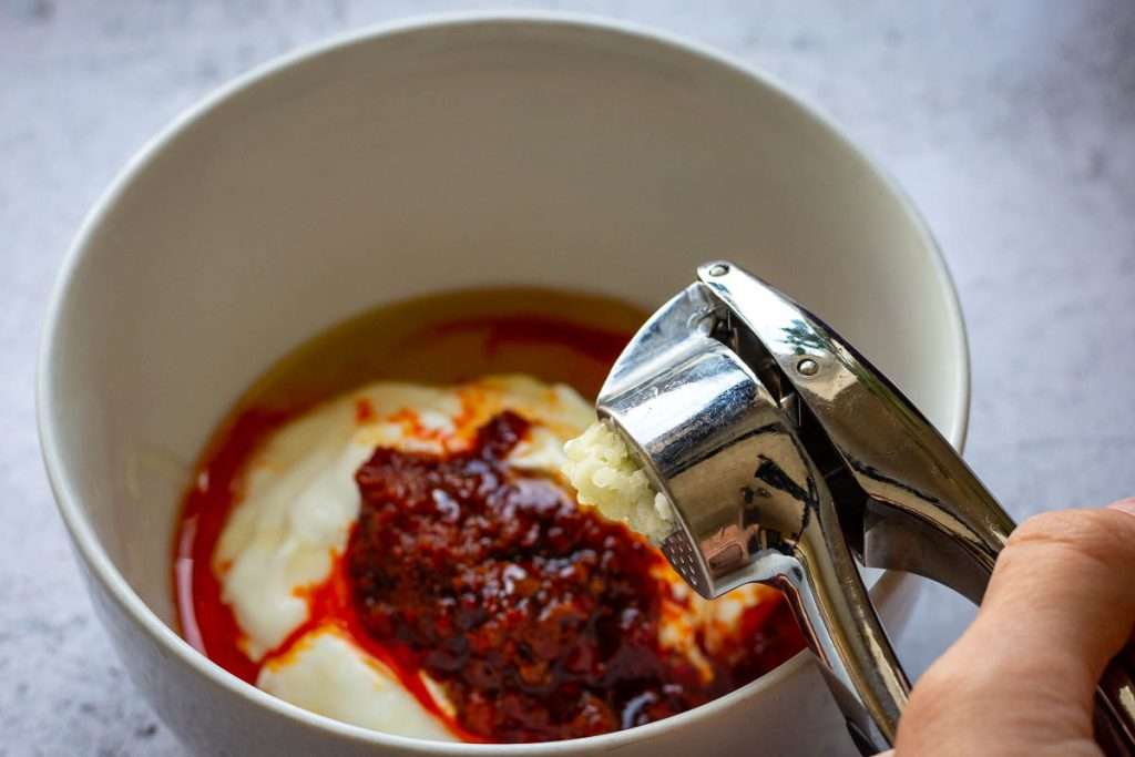 Garlic being added to the other harissa yogurt ingredients.