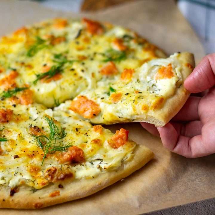 A slice of smoked salmon pizza being picked up.