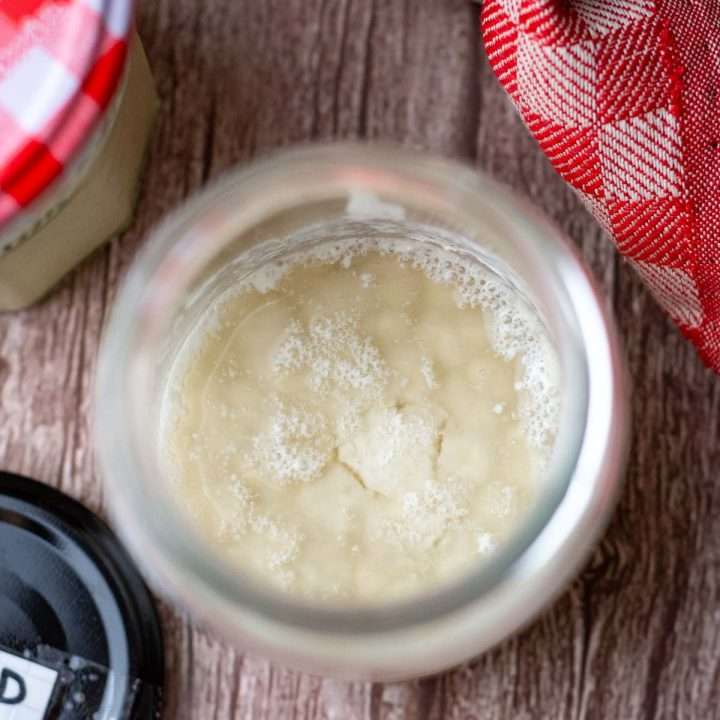 A jar with sourdough starter that has hooch on top.
