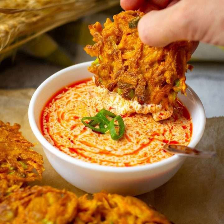 Harissa Yogurt Sauce being used as a dip for carrot fritters.