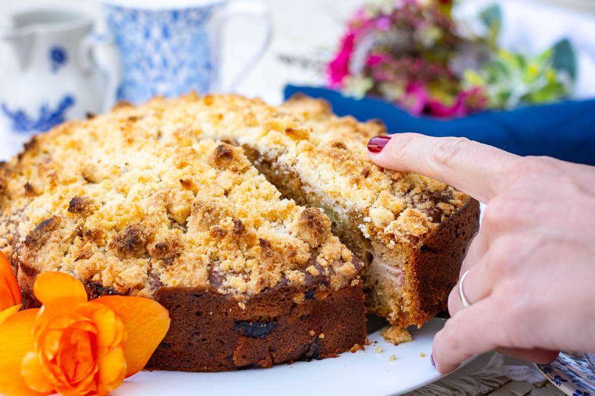 Sourdough cake with rhubarb and streusel topping having its first slice cut.
