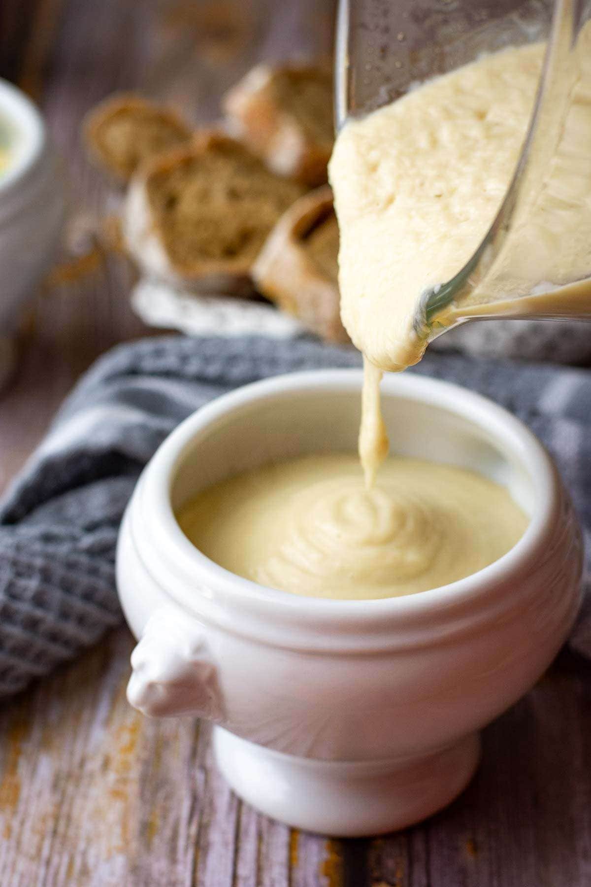 Pouring creamy cauliflower soup into a soup bowl.