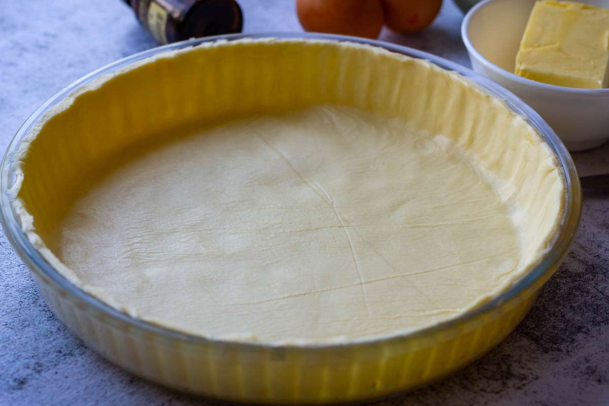 Shortcrust pastry tart case with overhanging edges trimmed flush to the tart tin.