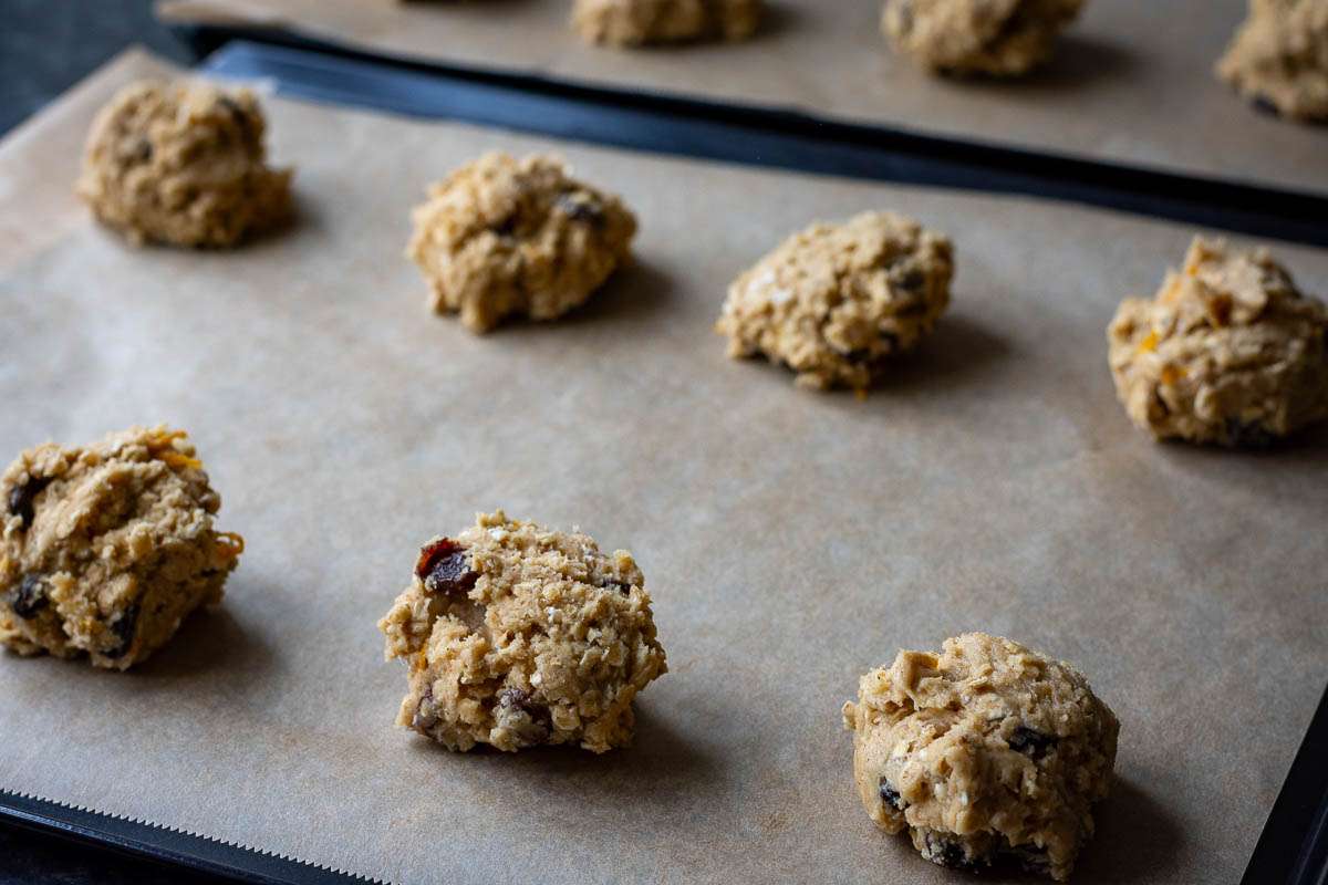 Sourdough oat and raisin cookies spaced out on two baking sheets.