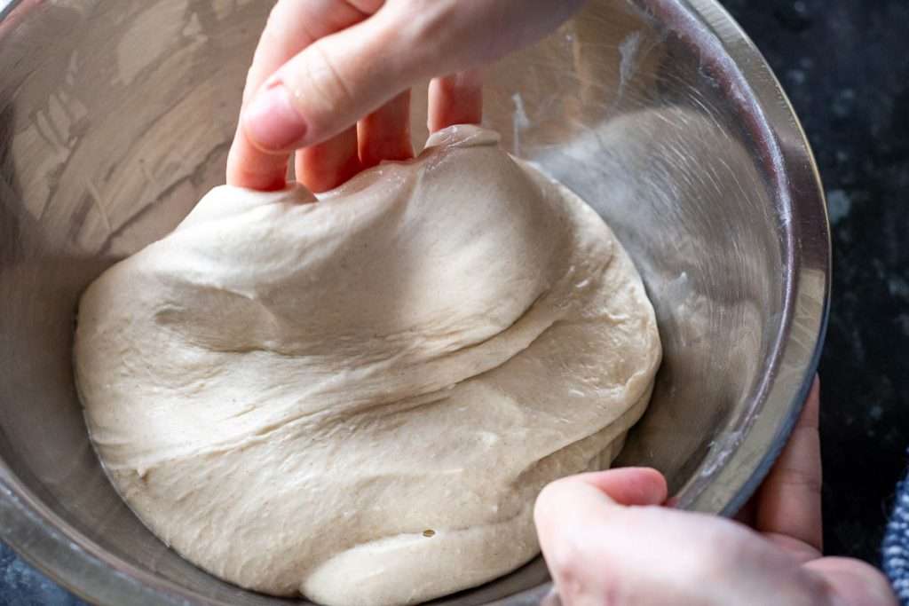Stretching one side of sourdough dough upwards.