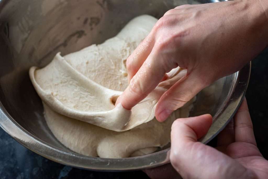 Placing the stretched out dough over the remaining sourdough.