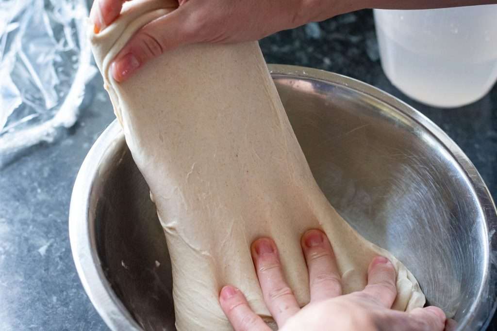 Stretching the sourdough holding the rest of it with the other hand.