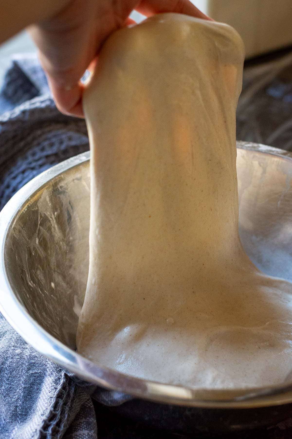Sourdough being stretched and folded in a metal bowl.