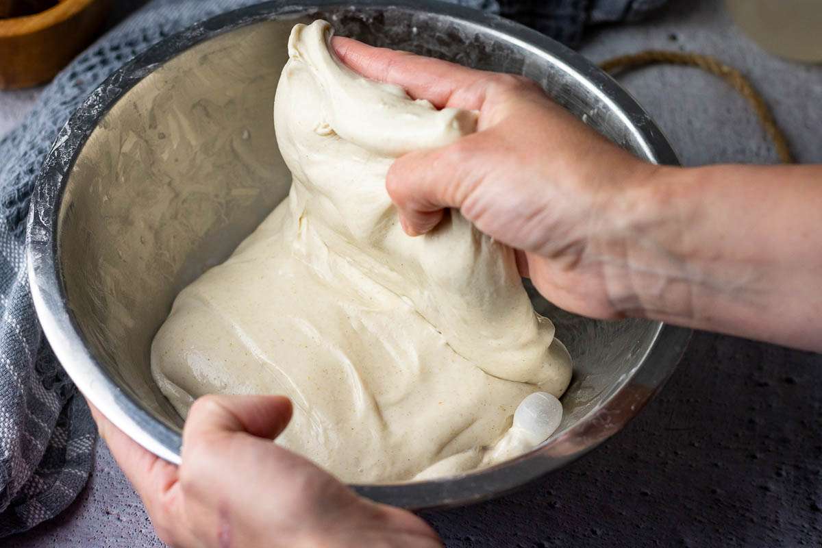 Folding sourdough over in a large mixing bowl.