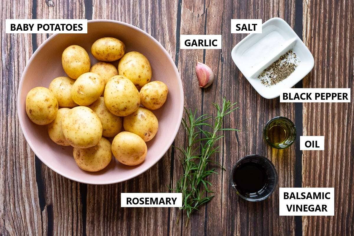 Ingredients for Balsamic roast potatoes on a wooden table.