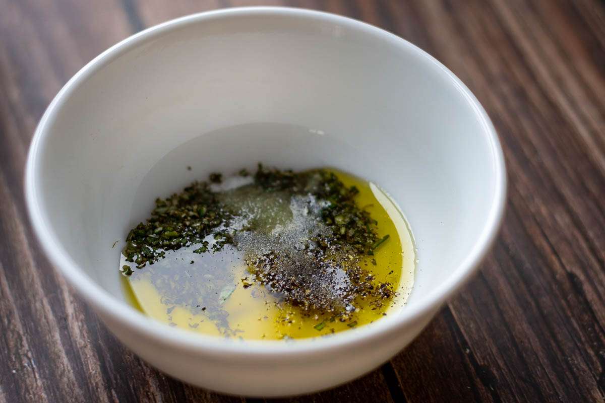 Olive oil drizzle with rosemary in a small bowl.