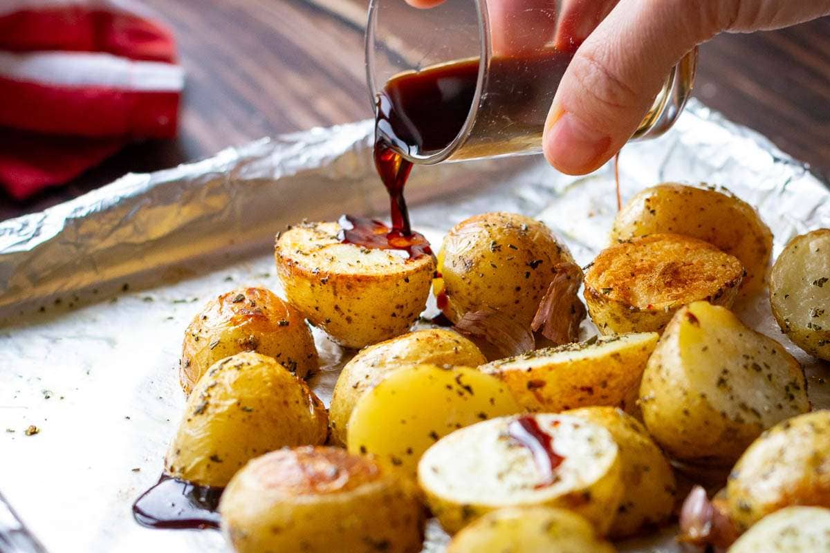 Pouring the balsamic vinegar over the potatoes halfway through cooking.