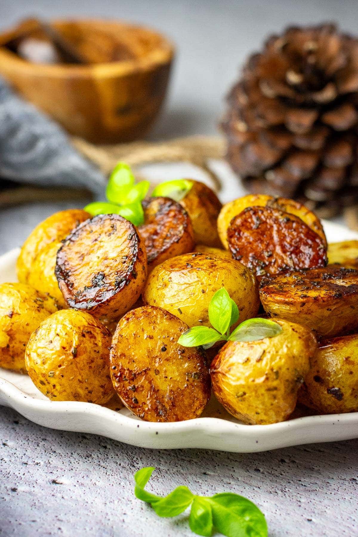 Balsamic Potatoes on a white plate garniched wit hsprigs of herbs.