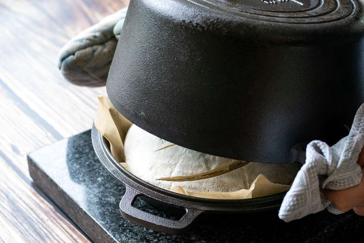 The bottom of the Dutch oven being plceed over the bread on the lid.