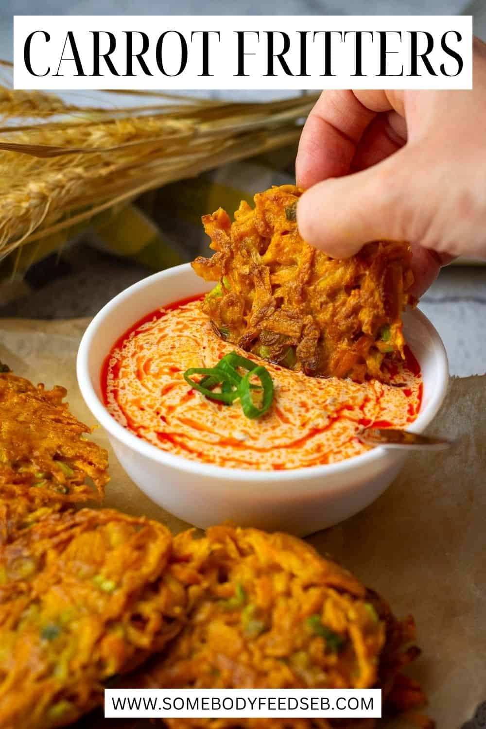 Crispy carrot fritters on a wooden board with one of them being dipped into harissa yogurt. Pin for Pinterest.