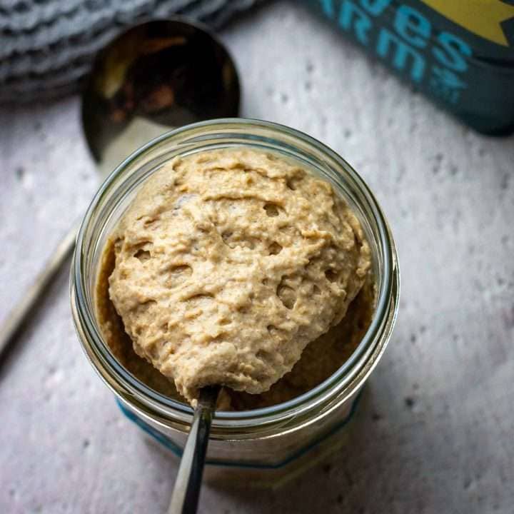 Rye sourdough starter being scooped out of a jar with a spoon.