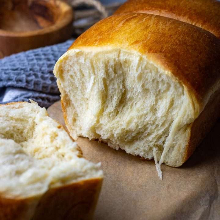 A piece of sourdough milk bread torn off from the rest of sourdough shokupan.