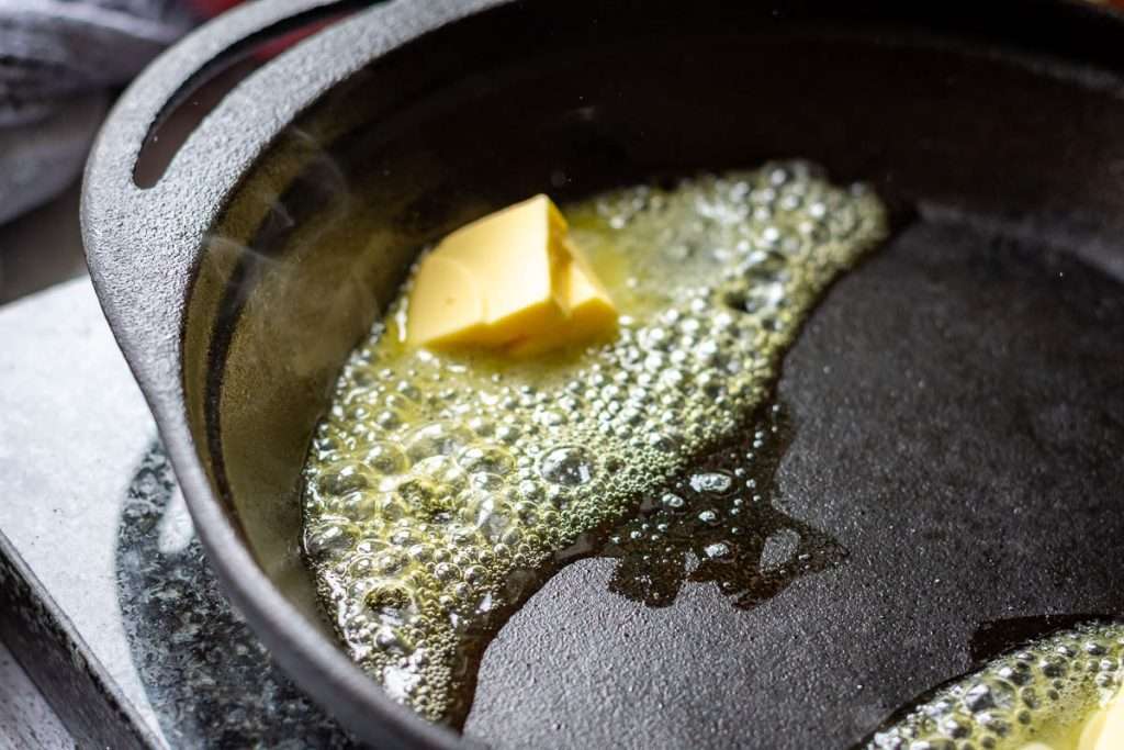 Butter melting in a preheated cast iron skillet.